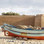 kasbah de Hammamet vue depuis la plage, barque de pêche au premier plan