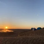 source chaude de Ksar Ghilane fumante dans les dunes au lever du soleil, campement