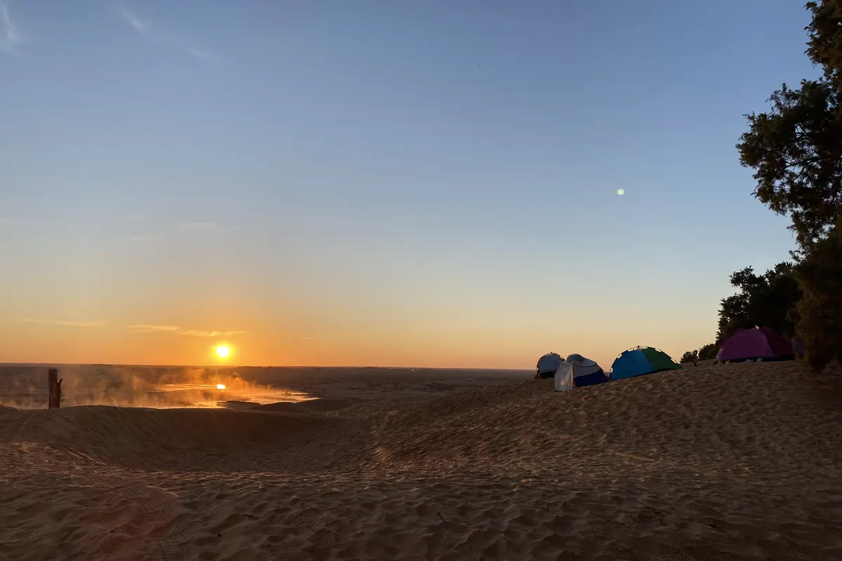 source chaude de Ksar Ghilane fumante dans les dunes au lever du soleil, campement