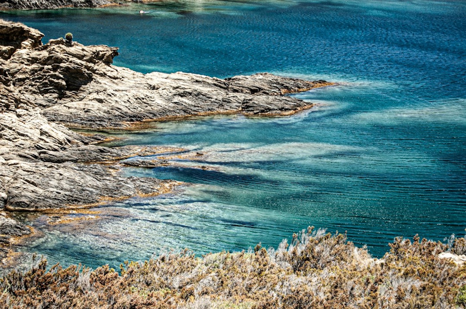 Plage méditerranéenne sauvage bordée de rochers et d'eau claire